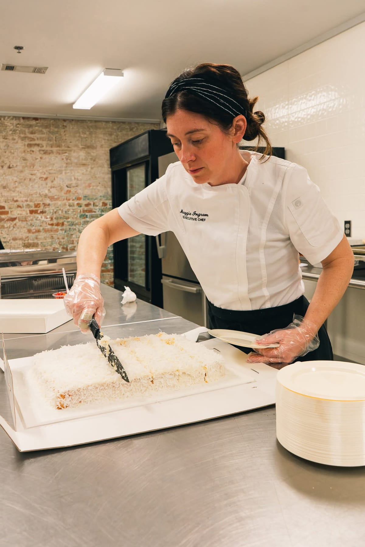 Chef Maggie Ingram plating a fresh coconut cake in her kitchen