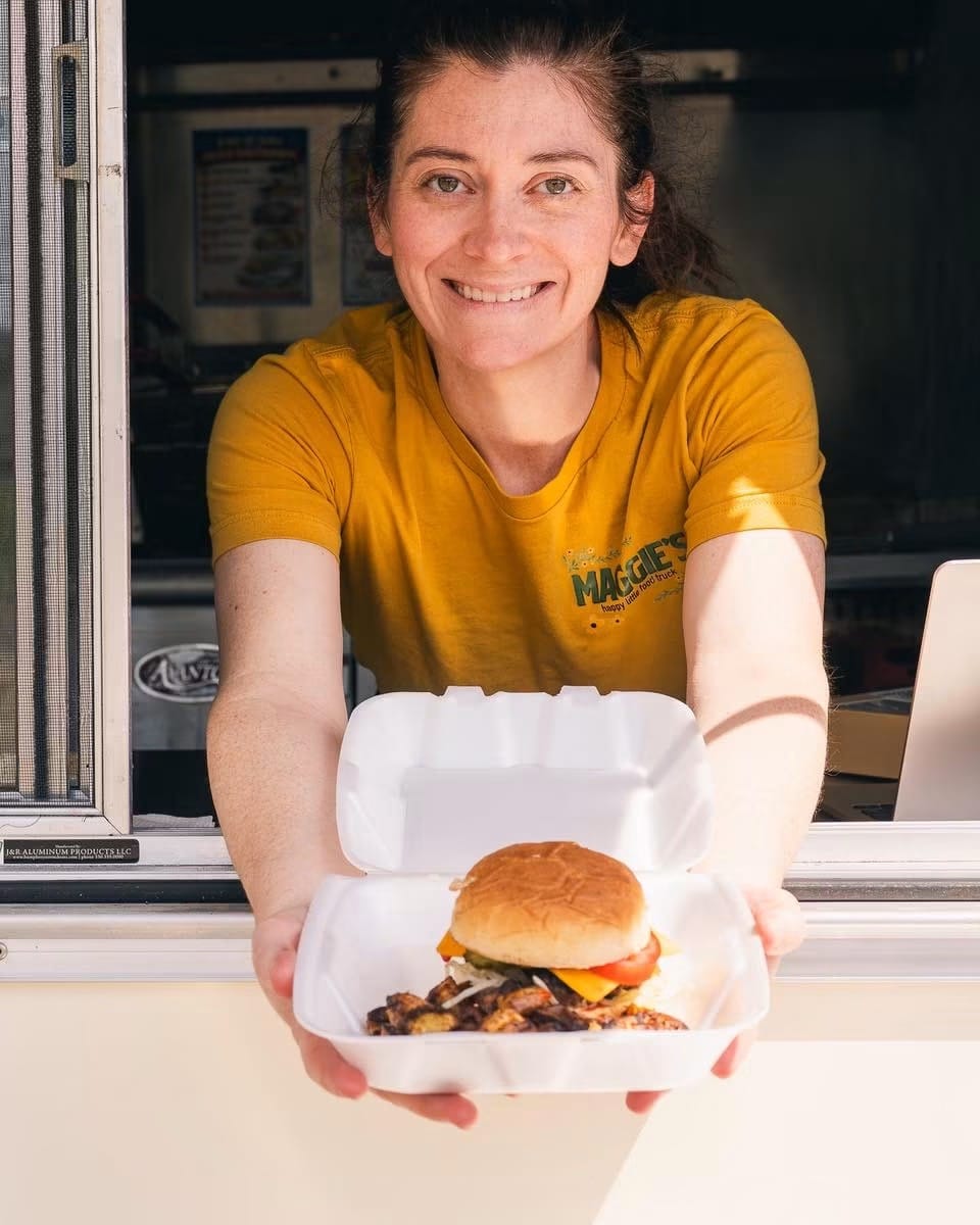 Maggie handing a fresh burger box out the food truck window